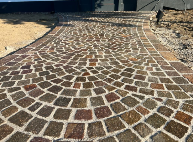 Gepflasterter Weg mit spiralförmigem Muster aus bunten Steinen.
