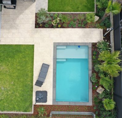 Gartenansicht mit einem Pool, grasbewachsenen Flächen und Terrassenmöbeln.