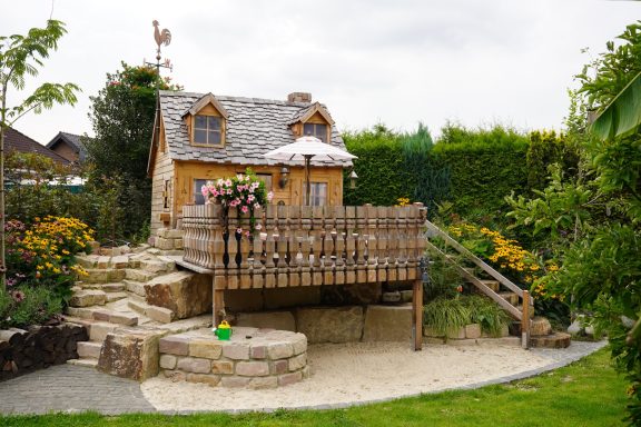 Landeinfamilienhaus mit Holzterrasse, Spielplatz und blühendem Garten.