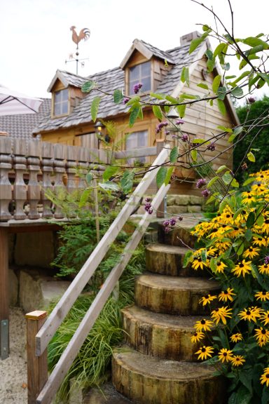 Holztreppe mit gelben Blumen und einem Haus im Hintergrund.